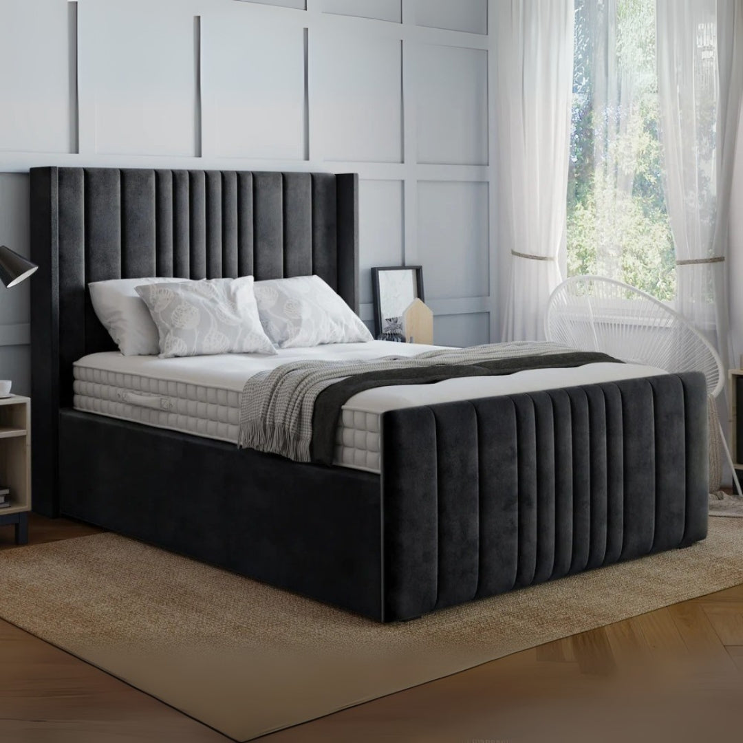 Gray upholstered bed in a modern bedroom setting with light gray walls and a window.